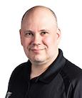 Headshot: Man in black shirt smiling at the camera.